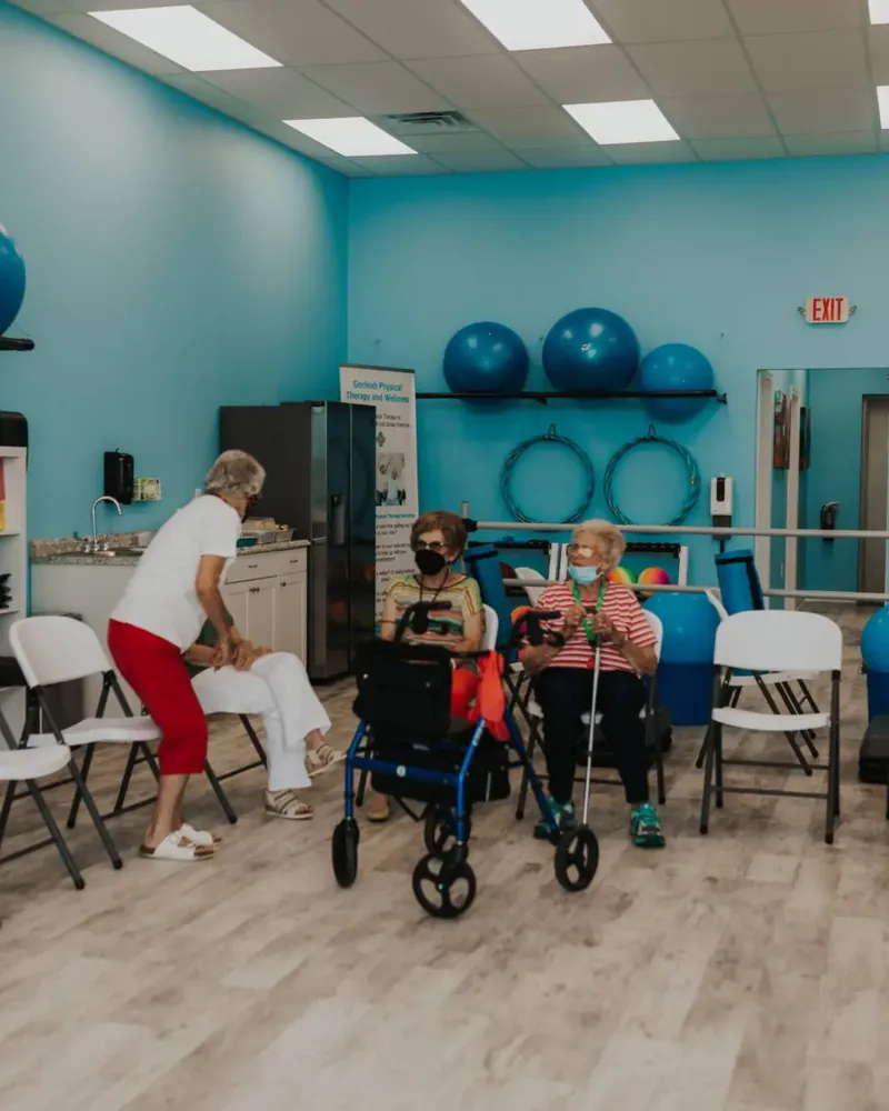 Therapist working with seated patients in the GeriHab clinic gym